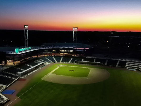 Atrium Health Ballpark at dusk, floodlights over the diamond